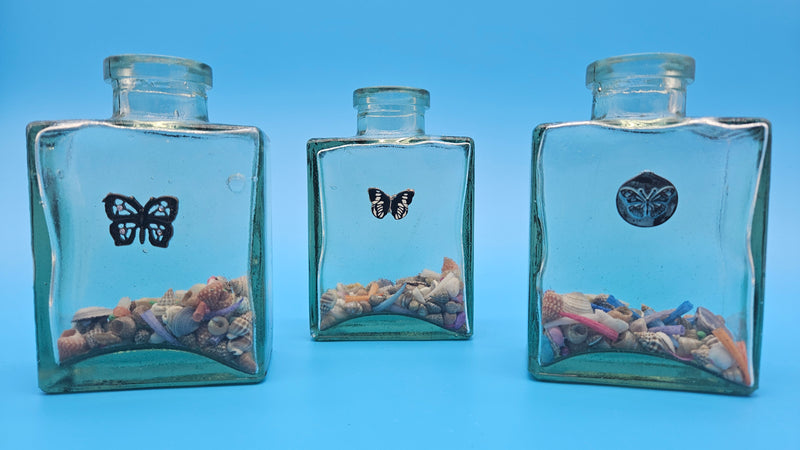 Glass bottle with bronze butterfly accent and seashell fill – coastal decorative home accessory