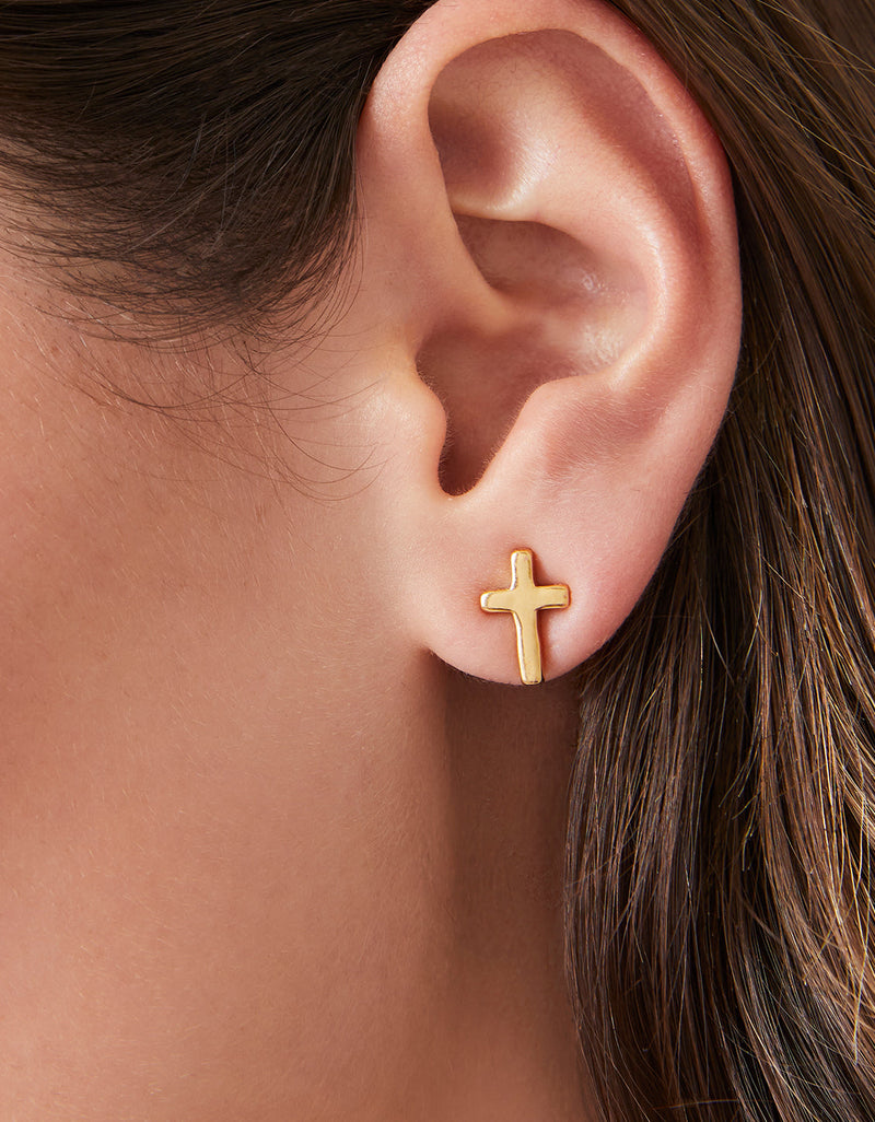 Cross stud earrings in 14kt gold vacuum plating worn on a model for a close-up view.