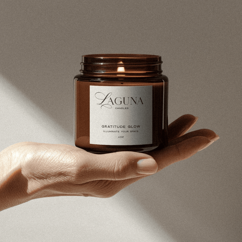 Brown candle jar labeled 'Laguna' held in a hand against a neutral background