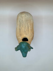 Top view of a vintage terra cotta sheep chia pet with a green-glazed head and an open cavity for planting.