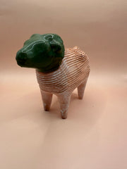 Front view of a vintage terra cotta ram chia pet with a green-glazed head and a textured, tan body.