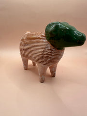 Side angle of a vintage terra cotta ram chia pet, showing the intricate detailing of the textured body and the smooth green-glazed head.