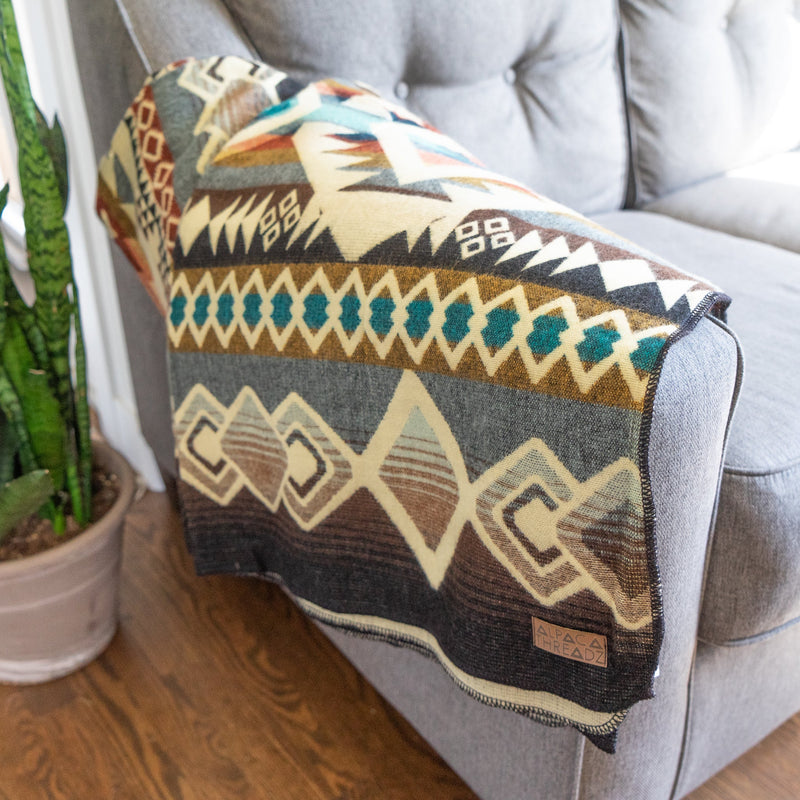 Wider shot of the Inca Andean Alpaca Wool Blanket draped over a couch in a living room, highlighting its size and decorative appeal.