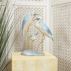 A decorative polystone bird family sculpture in light blue with yellow accents, displayed in a coastal-themed home.