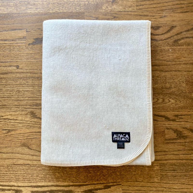 Light Grey Camp Throw Blanket with cozy woven texture, neatly folded on rustic wooden surface, soft neutral color perfect for modern, cabin, or coastal décor