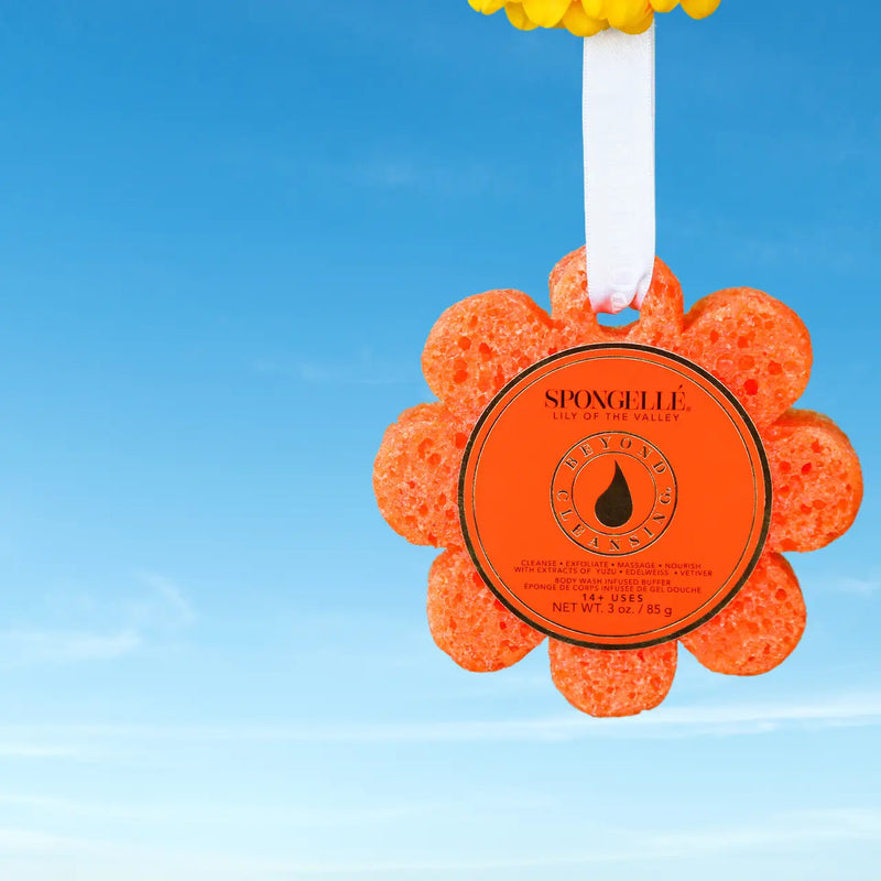 Orange flower-shaped sponge with a brand label against a blue sky