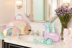 Aqua mermaid hairbrush displayed on vanity with pastel beauty accessories.