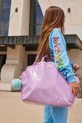 Girl carrying Mermaid Shell Overnight Bag over her shoulder with teal pom accent visible.