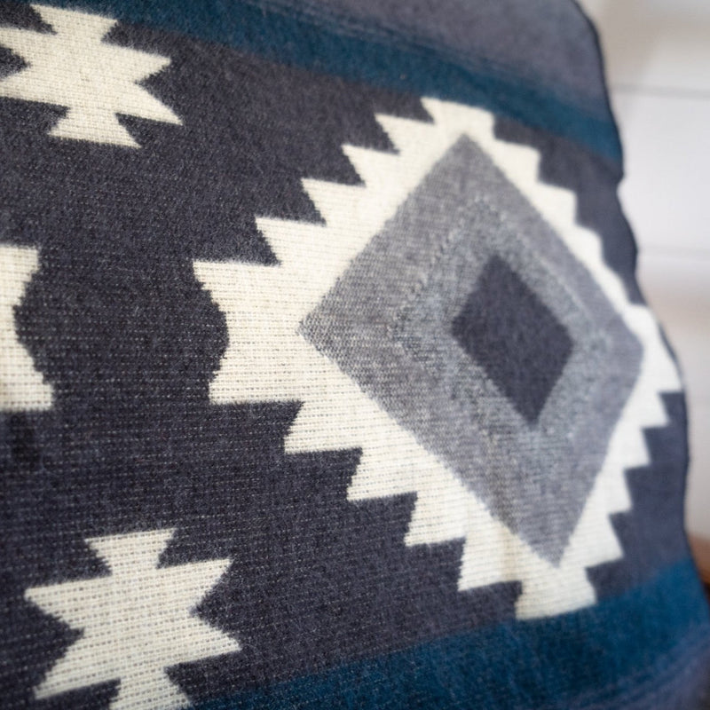 Midnight Blue & Grey Blanket folded and placed flat on the seat of a patterned armchair.