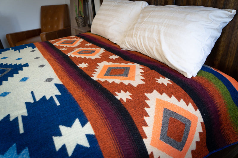 Corner of the Queen-size Alpaca Wool Blanket in Moab design, draped over a bed showing the vibrant pattern detail.