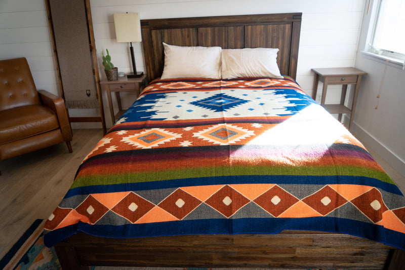 The Moab geometric Alpaca Wool Blanket draped fully over a Queen bed, showcasing the rich pattern symmetry.