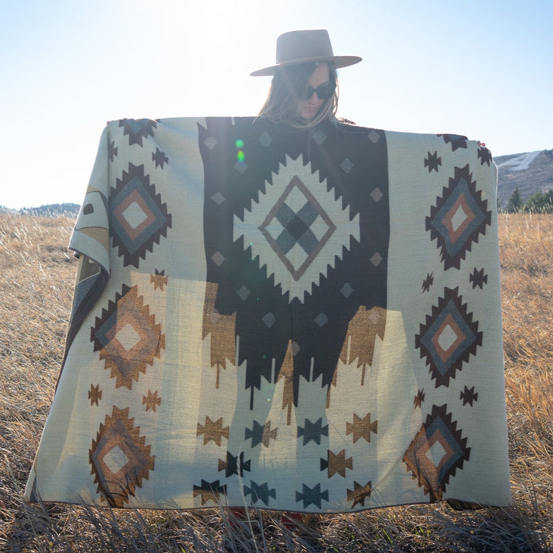 Woman holding the Mojave blanket behind her, highlighting the central diamond and geometric star motifs.