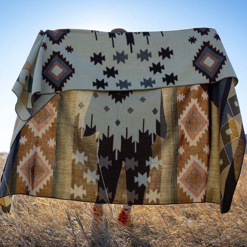 Mojave alpaca blanket folded horizontally and draped across a woman's back in a sunny, grassy field.
