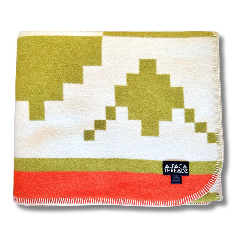 Folded corner view of the Moss/White/Green geometric alpaca blanket variant.