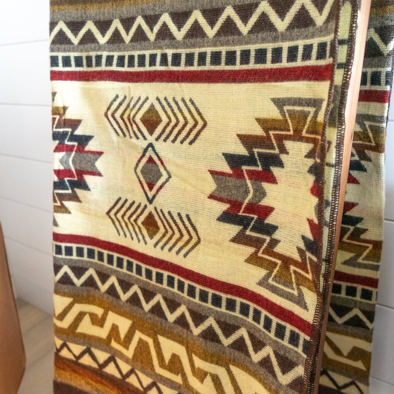 Close-up of the Mountain Alpaca Blanket, tightly folded to highlight the detail of the cream, red, and brown geometric bands.