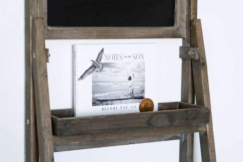 Wooden easel with a blackboard surface and a magazine on a white background