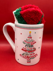 White ceramic mug with pink ornament Christmas tree design paired with red fuzzy socks.