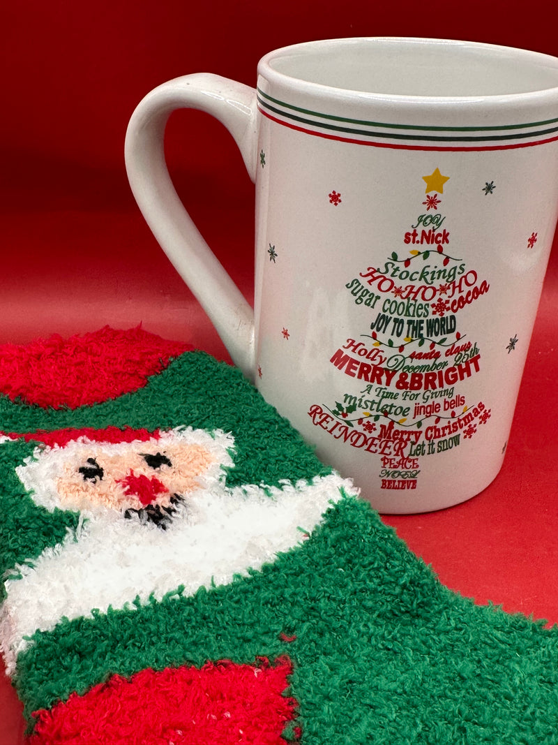 White ornament Christmas tree mug displayed beside fuzzy red and green holiday socks.
