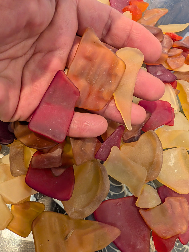 Close-up of a hand holding Hand Tumbled Seaglass in sunset colors