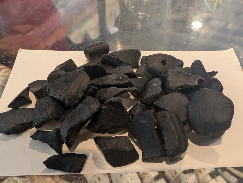 Frosted opaque black sea glass pieces displayed on a flat surface.