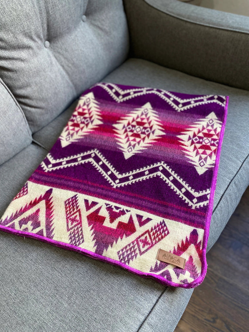 Close-up of the Pink/Magenta Alpaca Baby Blanket, tightly folded to highlight the contrasting colors and woven design.