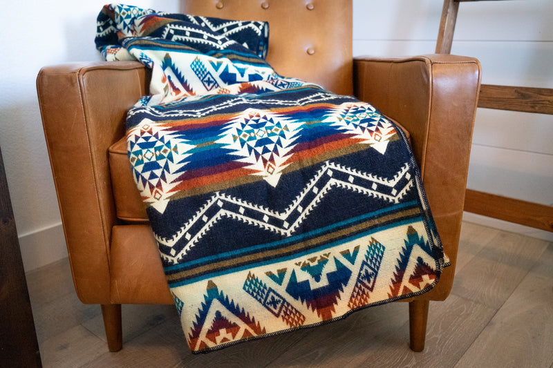 Rio Alpaca Blanket fully draped over the back of a brown leather armchair, showcasing the full pattern length.
