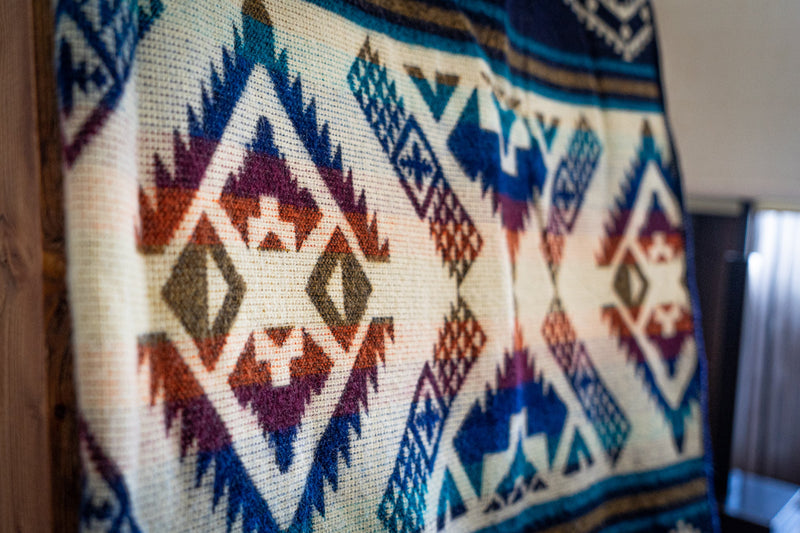 Tight close-up of the Rio Alpaca Blanket showing the intricate navy, red, and blue diamond geometric pattern in high detail.