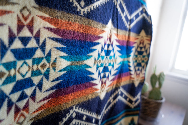 Extreme close-up of the Rio blanket's intense color saturation, focusing on the blue, terracotta, and white geometric motifs.