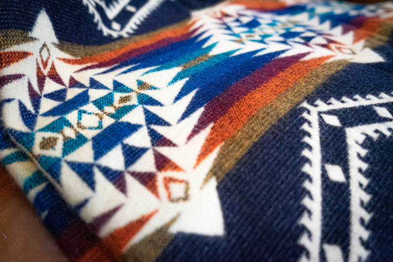 Close-up of the Rio blanket's geometric pattern, focusing on the navy, white, rust orange, and teal color accents.