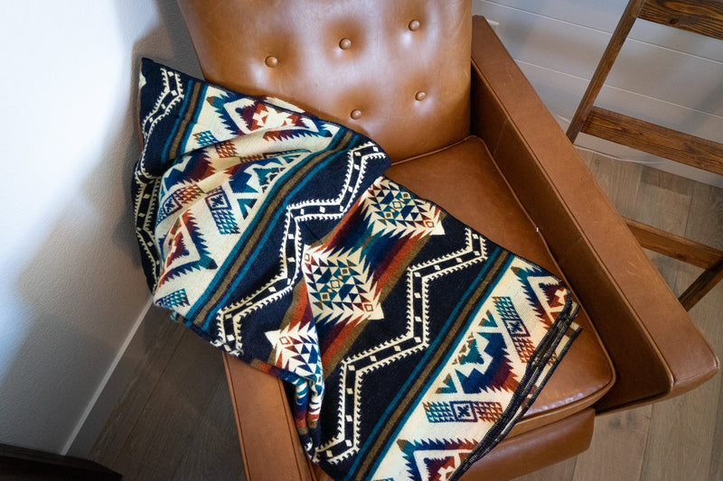 Rio Alpaca Throw folded diagonally and resting on a brown leather armchair, highlighting the dense pattern.