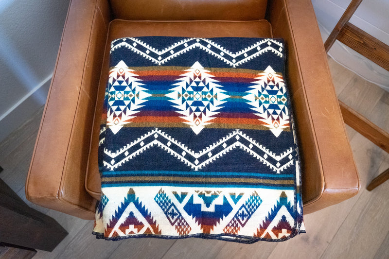 Rio Alpaca Throw folded into a clean rectangle and placed flat on a light wooden chair.