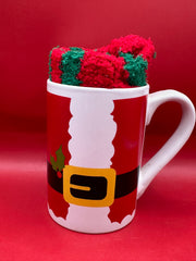 Santa suit design mug filled with fuzzy red and green Christmas socks.