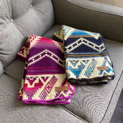 Stack of three folded Alpaca Baby Blankets: Blue/Cream, Pink/Magenta, and Tan/Brown, showcasing all color options.