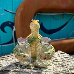 Resin sea turtle salt and pepper shaker holder with detailed shell and two glass shakers on a coastal tabletop.