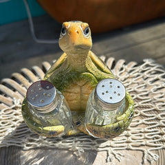 Resin sea turtle salt and pepper shaker holder with detailed shell and two glass shakers on a coastal tabletop.