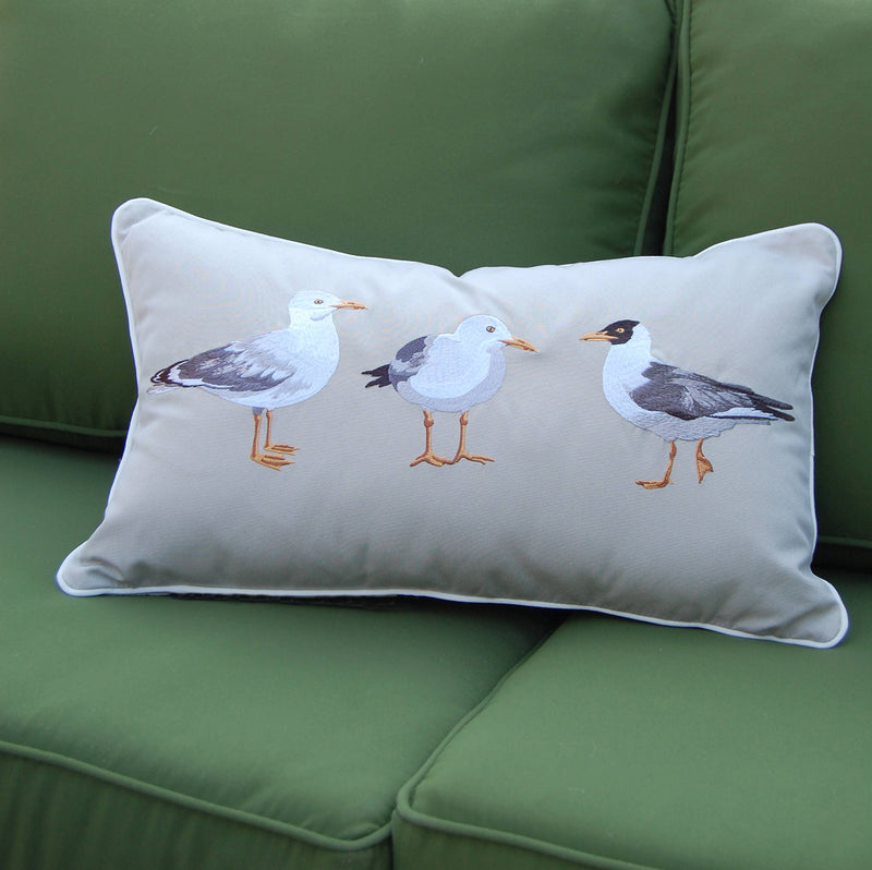 Seagull Indoor/Outdoor Pillow with embroidered seagulls on a light grey background, displayed on a green patio chair.