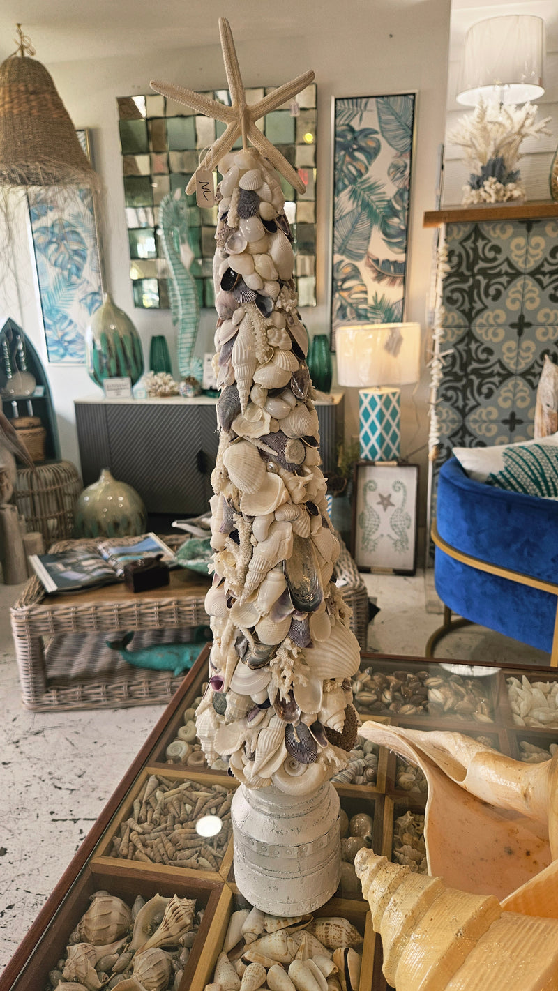 Seashell tree resting on its white pedestal base, with natural shells and other small decor items visible on the tabletop below.