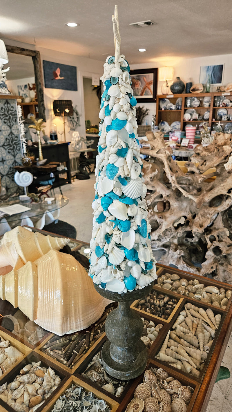 Angled view of the seashell tree, highlighting the contrast between the vibrant turquoise and white shells on the dark pedestal base.