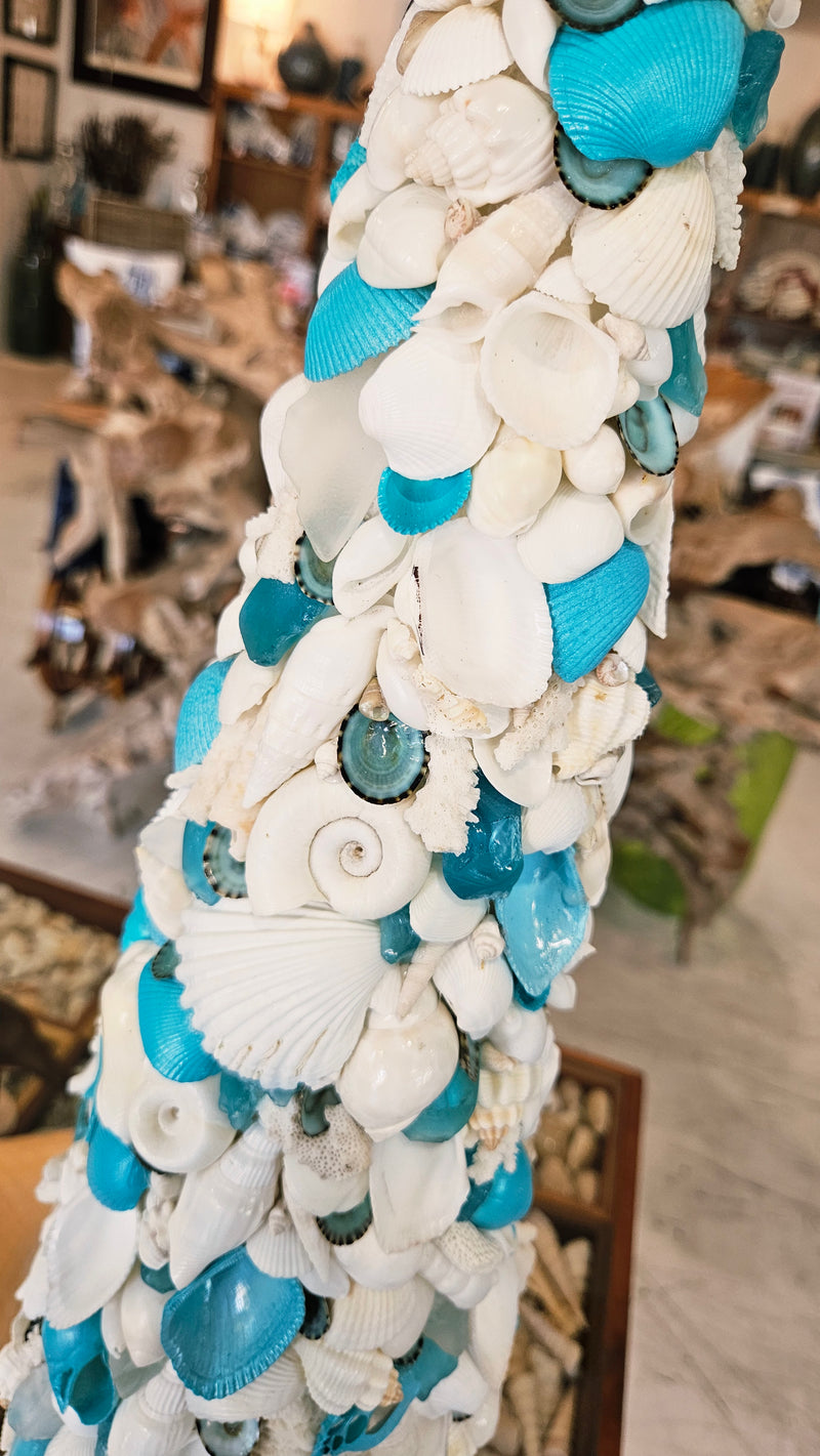 Vertical crop detail of the seashell tree's body, highlighting the tight, dense arrangement of the mixed white and turquoise shells.