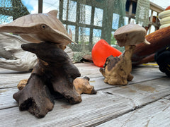 Shark and Hammerhead Driftwood Sculptures side by side on a wooden surface with nautical elements