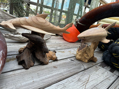 Shark and Hammerhead Driftwood Sculptures side by side on a wooden surface with nautical elements