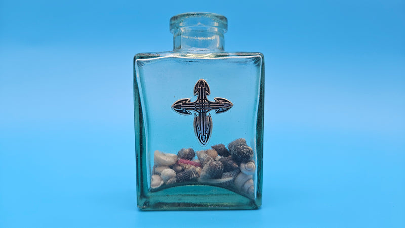Shell-filled glass jar with bronze cross accent – inspirational beach house decor