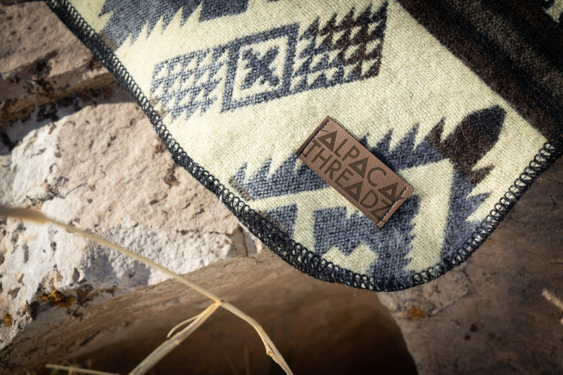 Tight close-up of the Slate blanket's patterned edge draped over a rock, showing the clean finish and thick weave.