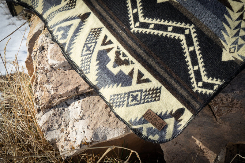 Close-up of the Slate blanket's pattern draped over a brown rock, showing the contrast between the dark and light geometric sections.