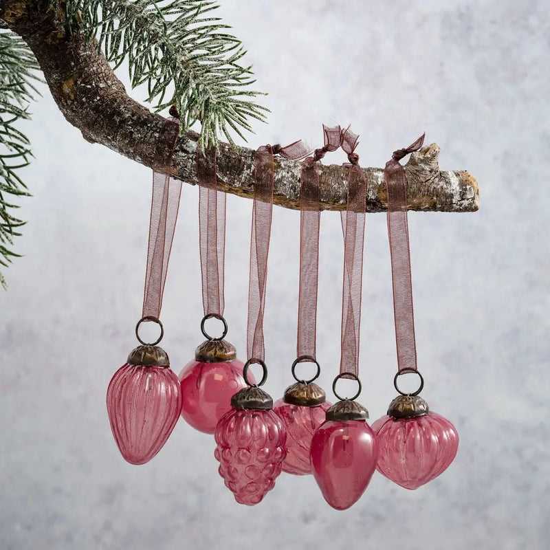 Small mixed design 1" mauve luster glass baubles, hand-blown, hanging from a branch, translucent finish with ornate caps.