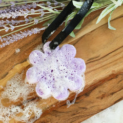 A close up of a soapy purple Spongelle sponge. 