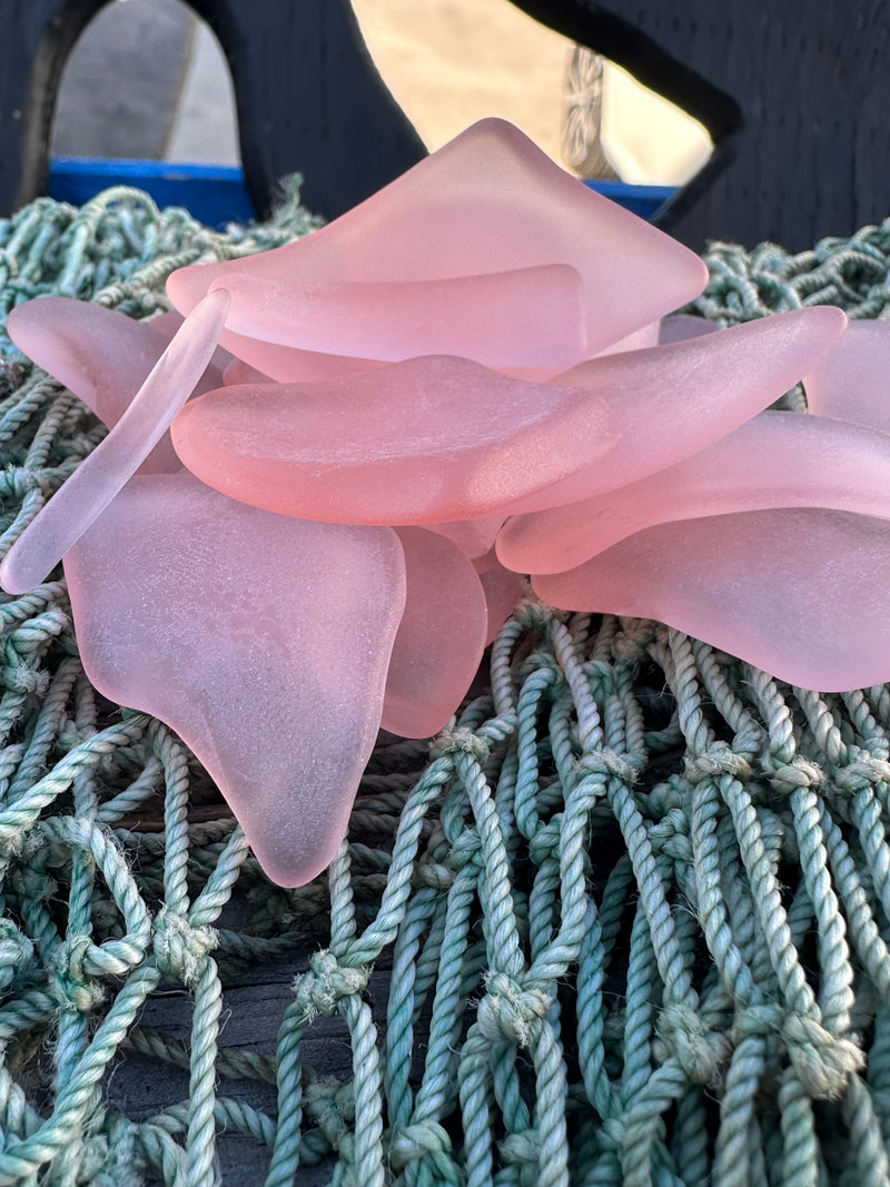 Front angle close up of pink sea glass on a net.