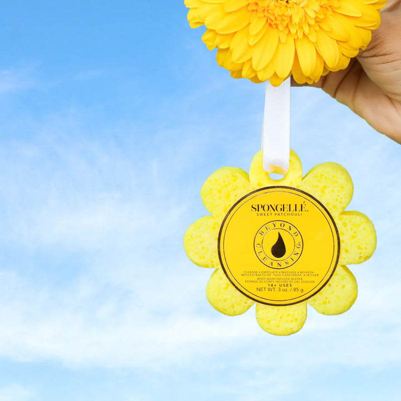 Yellow flower-shaped sponge with a brand label against a blue sky