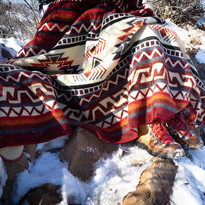 Close-up of the Wildfire blanket partially spread out and resting directly on the snow-covered ground, showing the pattern texture.