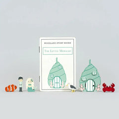Children's book titled 'The Little Mermaid' with cartoon houses and sea creatures on a light gray background